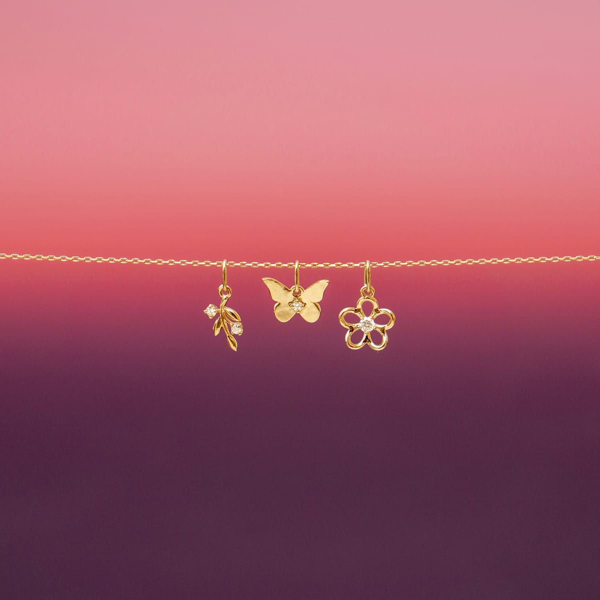 Tres dijes de oro: hoja, mariposa y flor